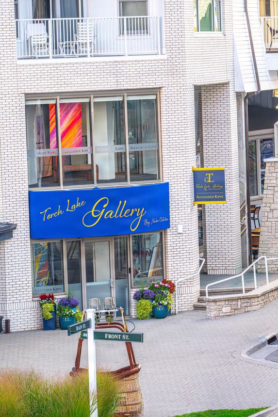 The gallery storefront on Main Street in Bay Harbor with a hot air balloon basket resting at the corner beside the Main Street and Front Street signs