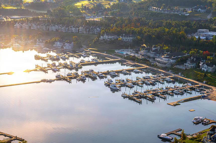 Aerial of the marina docks and moored boats under a low misty sun