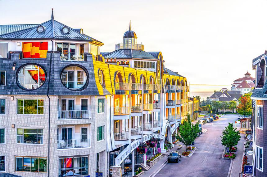 Aerial view along the rooftops of Bay Harbor's Main Street at sunrise, round dormer windows catching the light, the Inn at the far end