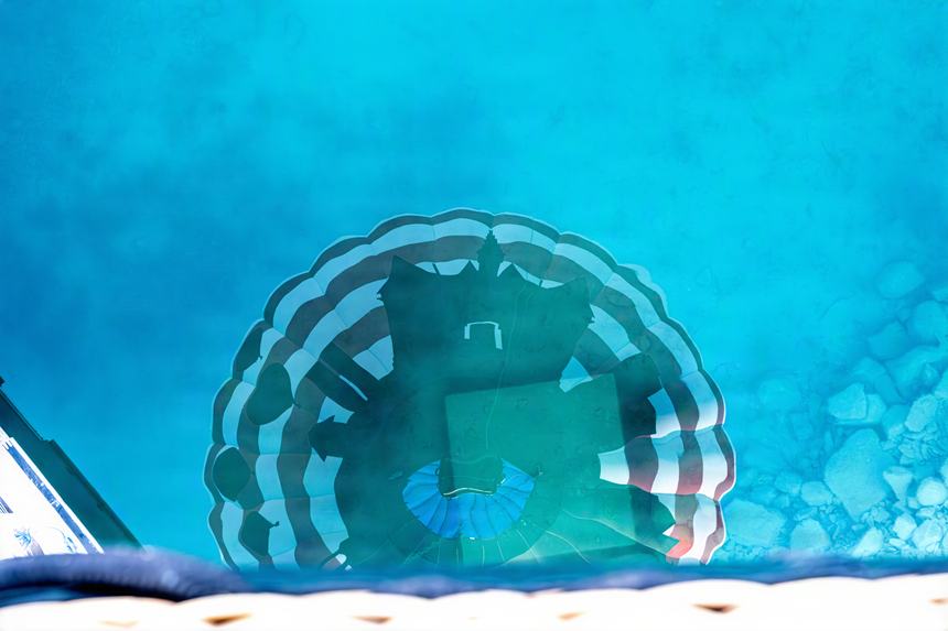 Abstract view down from a balloon basket of the balloon's own reflection rippling across turquoise water